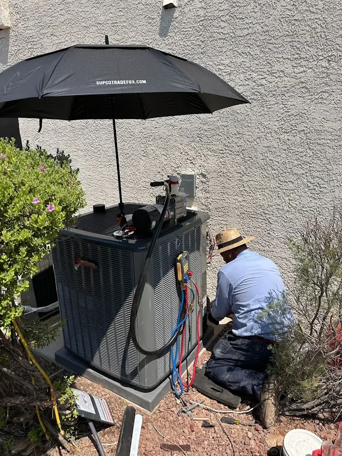 HVAC technician performing outdoor AC maintenance in Ashburnham